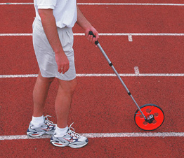 Man measuring a track with a circular measuring wheel